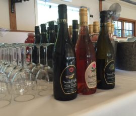 Three bottles of Yamhill Valley wine are displayed on a table with wine glasses and an ice bucket in the background.